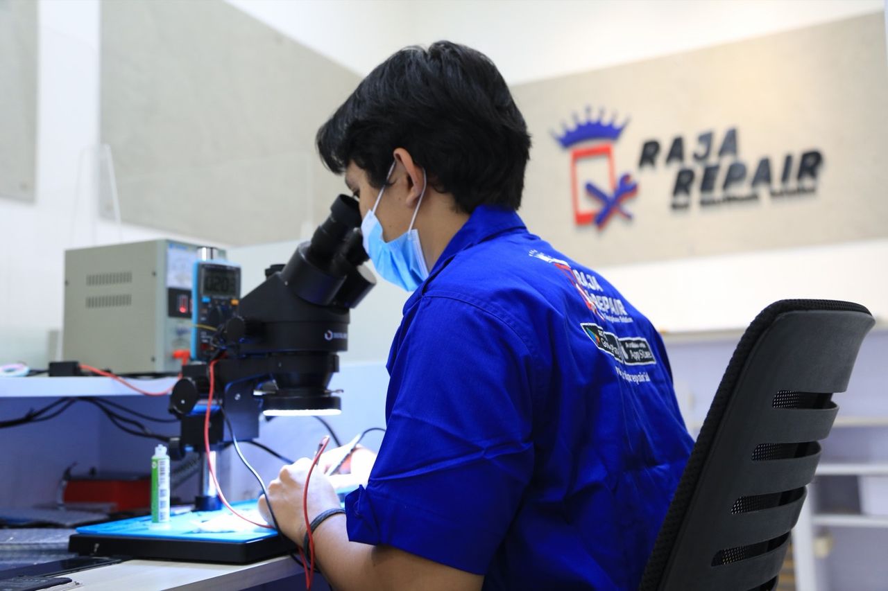 Teknisi Raja Repair sedang memperbaiki smartphone